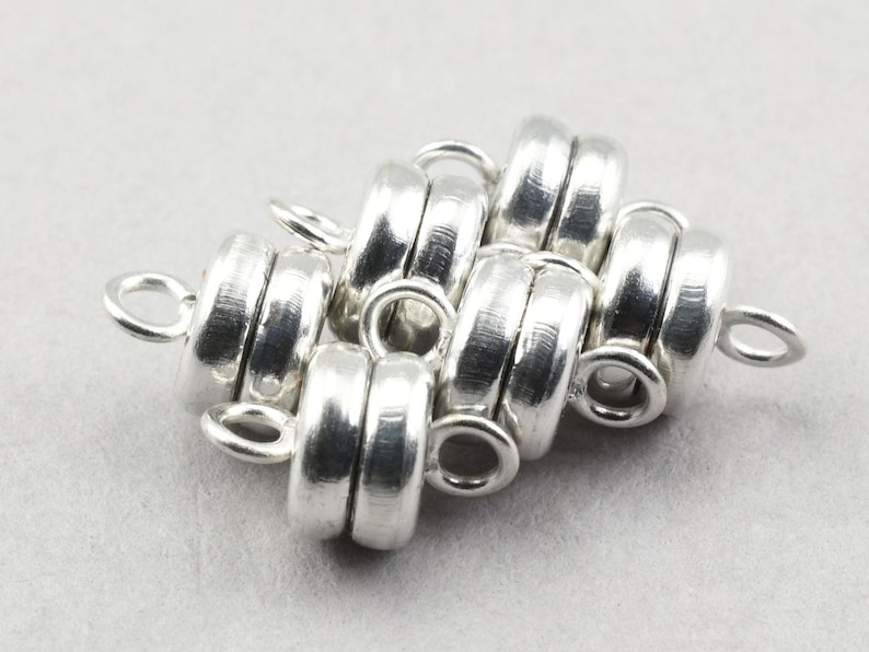 May include: Silver magnetic clasps for jewelry making. The clasps are round and have a smooth, polished finish. They are designed to be used with necklaces, bracelets, and other jewelry pieces.