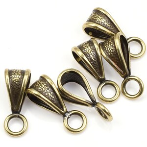 May include: Five gold-toned metal pendant bails with a textured surface. Each bail has a loop on either end.