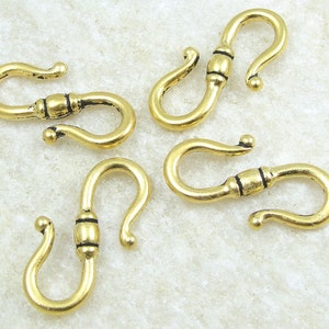 May include: Five gold-toned metal lobster clasps with black accents. The clasps are designed with a curved shape and a small bead in the center.