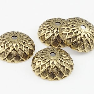May include: Three gold-toned metal decorative caps with a flower-like design. The caps have a small hole in the center.