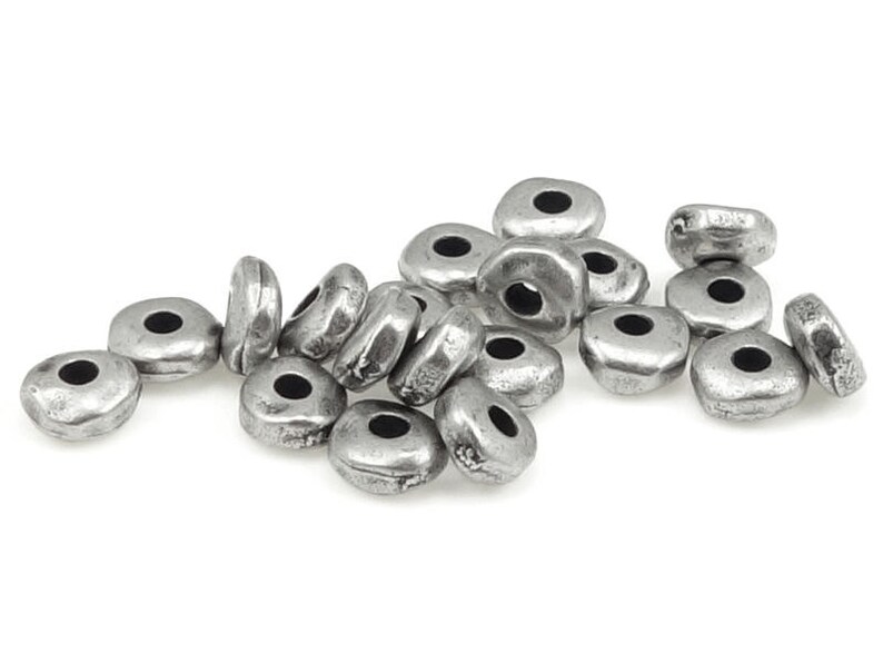 May include: A collection of silver-colored, irregularly shaped beads with a central hole. The beads have a slightly hammered texture and a matte finish. These beads are suitable for jewelry making and crafting projects.