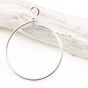 May include: A silver hoop earring with a simple, twisted wire closure.