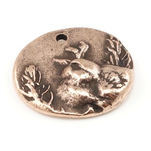 May include: A copper-colored metal charm featuring a detailed, three-dimensional design of a bird perched on a branch. The charm has a hole at the top for attaching to a necklace or bracelet.