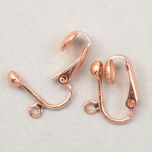 May include: Two rose gold-colored clip-on earring findings. Each finding has a curved lever, a small ball, and a loop for attaching a charm. The findings are designed for non-pierced ears.