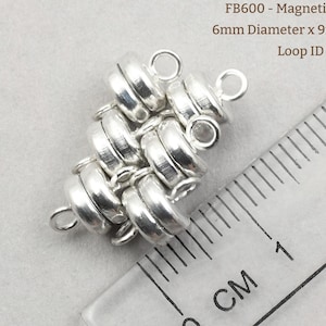 May include: Silver magnetic clasps with a 6mm diameter and 9mm height. The clasps are made of multiple interlocking rings and have a loop with a 1.8mm inner diameter. FB600 - Magnetic Clasps 6mm Diameter x 9mm Tall Loop ID ~1.8mm