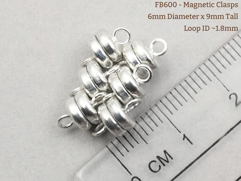 May include: Silver magnetic clasps with a 6mm diameter and 9mm height. The clasps are made of multiple interlocking rings and have a loop with a 1.8mm inner diameter. FB600 - Magnetic Clasps 6mm Diameter x 9mm Tall Loop ID ~1.8mm