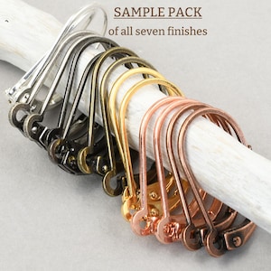 May include: A sample pack of seven different metal earring hook finishes. The hooks are displayed on a white, textured stick. Finishes include silver, black, gold, and copper tones. The text "SAMPLE PACK of all seven finishes" is visible.