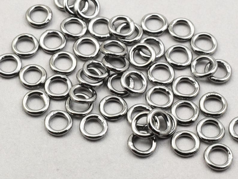 May include: A large pile of silver jump rings. The rings are all the same size and are arranged in a random pattern.