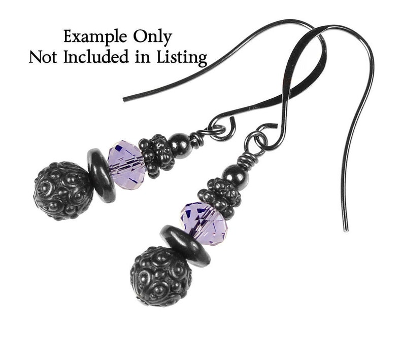 May include: A pair of dangle earrings with black metal wire and beads. The earrings feature a purple crystal bead and a black metal bead with a textured surface.