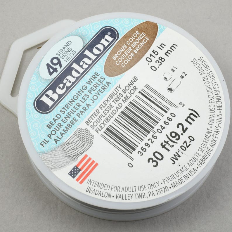 May include: A spool of 30 feet (9.2 meters) of Beadalon bronze bead stringing wire. The wire is 0.015 inches (0.38 mm) in diameter. The spool is white with a blue and white American flag.
