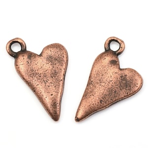 May include: Two antique copper heart charms with a loop at the top for hanging. The hearts have a distressed, rustic finish.