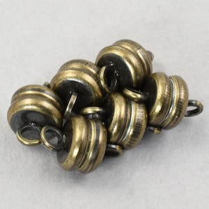 May include: A group of six antique gold-toned metal toggles with a decorative grooved design. The toggles have a loop on one end and a flat surface on the other.