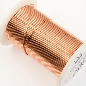 May include: A spool of rose gold colored wire. The wire is wound tightly around the spool and is ready to be used for crafting projects.