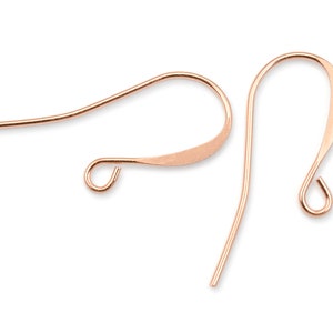 May include: Two rose gold earring hooks. The hooks are made of metal and have a smooth, curved shape.