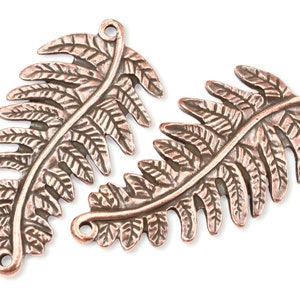 May include: Two copper-colored fern leaf charms with a detailed design. Each charm has a hole at the top for attaching to jewelry or other crafts.