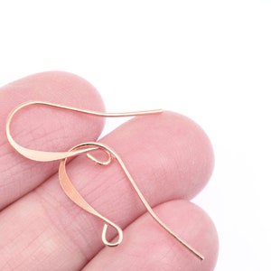 May include: Rose gold ear wire with a curved, flat design. The wire is bent into a loop at the top and bottom.