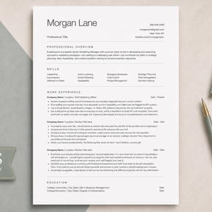 May include: A white resume template with black text featuring the name Morgan Lane, professional overview, skills, work experience, and education sections. A grey tag with the text ATS FRIENDLY is on the left, with a pen and paperclips nearby.