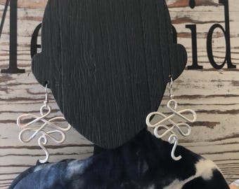 Pendientes de metal plateado martillado envueltos en alambre con forma de libélula.