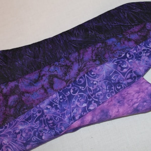 May include: Purple and black patterned oven mitt with a quilted design. The mitt is made of fabric and has a hanging loop.