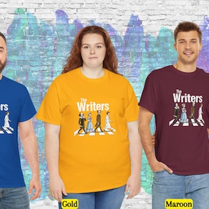 Puede incluir: Cuatro personas con camisetas azul real, doradas y granates. Cada camiseta tiene el texto "The Writers" sobre una ilustraci&oacute;n de figuras literarias cruzando un paso de cebra. El fondo es un mural colorido.