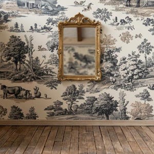 May include: A rectangular mirror with an ornate gold frame mounted on a wall covered in cream-colored wallpaper featuring a repeating dark gray pastoral toile pattern of trees, animals, and landscapes above a light brown wooden floor.