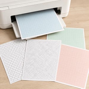 May include: A white printer with a light blue grid paper sheet emerging from the tray. Four additional sheets of paper are displayed below, featuring a black brick pattern, a gray honeycomb design, a light green grid, and a light pink grid pattern.