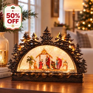 May include: A decorative arched nativity scene lantern featuring a dark brown, textured pine tree frame with integrated warm LED lights. Inside the glass arch, a miniature nativity set includes figures of the holy family and wise men.