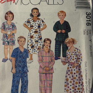 May include: A McCall's sewing pattern for children's pajamas. The pattern features various pajama styles, including short sets, long sets, and nightgowns. The pajamas have different patterns, such as teddy bears, smiley faces, and plaid. The pattern size is Y (Xsm-Sml).