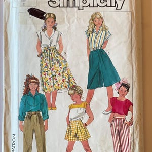 May include: Simplicity sewing pattern number 7405 for girls' clothing. The pattern includes five different styles: a white blouse with a skirt, a striped blouse with culottes, a blue shirt with pants, a yellow tank top with a plaid skirt, and a red tank top with striped pants.