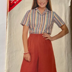 May include: A vintage sewing pattern envelope with a woman wearing a striped shirt and red pants. The pattern number is 5005 and the size is B (14-16-18).