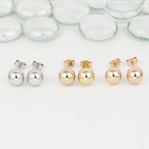 May include: Three pairs of ball stud earrings in silver, gold, and rose gold. The earrings are simple and elegant.