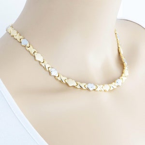May include: A gold and silver necklace with a heart-shaped link design.