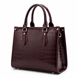 May include: A burgundy handbag with a crocodile skin texture. The bag features two top handles and gold-coloured hardware. The rectangular bag has a structured shape and a glossy finish.