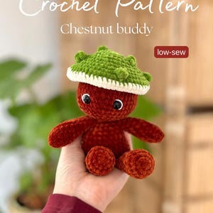Könnte beinhalten: Gehäkelte Kastanien-Buddy-Puppe mit grünem Hut und weißem Rand. Die Puppe hat einen roten Körper, Arme und Beine. Der Text "Crochet Pattern" und "Chestnut buddy" stehen oben. Der Text "low-sew" steht in einem roten Feld.