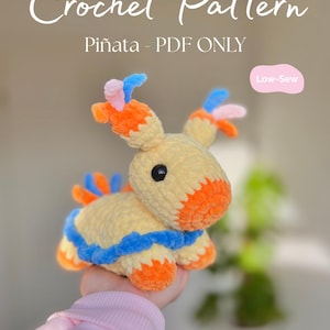 May include: A crocheted Piñata pattern in PDF format. The plush toy is yellow with orange, blue, and pink accents. The text "Crochet Pattern" and "Piñata - PDF ONLY" are displayed. The text "Low-Sew" is also visible.