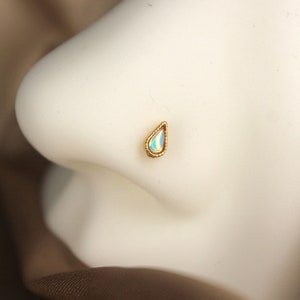 May include: A gold nose ring with a teardrop-shaped opal gemstone.