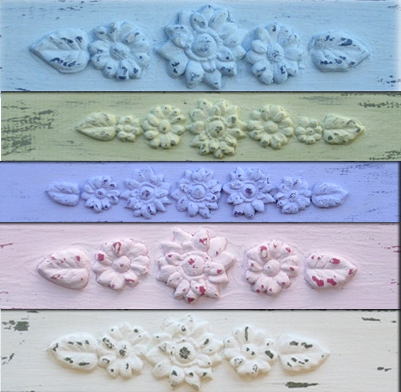 May include: Five wooden boards painted in different pastel colors, each with a row of five decorative floral designs. The designs are raised and have a distressed look. The colors are light blue, yellow, lavender, pink, and white.