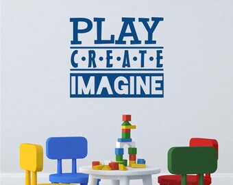 Puede incluir: Una escena de sala de juegos con una mesa blanca, sillas coloridas y bloques de construcción. La pared presenta las palabras "PLAY CREATE IMAGINE" en azul. Se ve una silla amarilla, azul, verde y roja.
