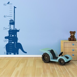 Pode incluir: Um gráfico de crescimento azul e branco com uma pilha de animais, incluindo uma girafa, um rinoceronte, um hipopótamo e um elefante. O gráfico está marcado em polegadas de 12 a 60.