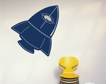 May include: A blue rocket ship decal on a white wall with a yellow chair in the foreground. The decal is a simple design with a rounded top and a pointed bottom. The chair is a modern design with a curved back and a wide seat. The text "Single Stone Studios" and "Original Artwork Copyright 2009" is at the bottom of the image.