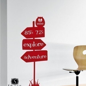May include: Red vinyl wall decal featuring a signpost with arrows pointing in different directions. The signpost has the words "explore" and "adventure" on it. There is an owl perched on top of the signpost. The decal also includes a small patch of grass at the base of the signpost.