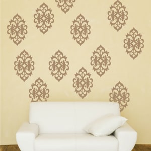 May include: A white couch with a brown throw pillow in front of a wall with brown decorative wall decals. The decals are in a geometric pattern.