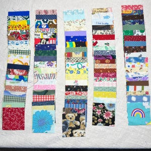 May include: Five columns of fabric swatches in various patterns and colours. The swatches include floral, geometric, and novelty prints. Some swatches have text, including "I love to play". The fabrics are arranged on a white surface.