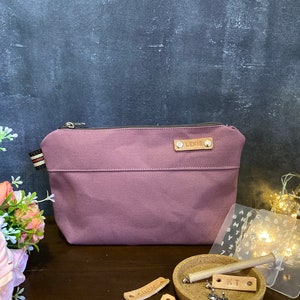 Könnte beinhalten: Ein Satz personalisierter Leder-Etiketten mit den Namen Lexie, Cindy, Maeve und Emi. Die Etiketten befinden sich auf einer Holzoberfläche mit einer kleinen Kork-Schale, die zwei Metallnieten und einen Holzstift enthält. Außerdem gibt es vier transparente Plastikfolien mit Buchstaben und Zahlen.