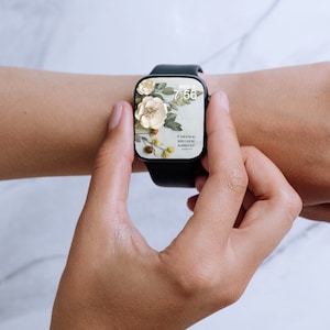 K&ouml;nnte beinhalten: Eine schwarze Smartwatch mit floralem Design auf dem Bildschirm, die die Uhrzeit 7:56 anzeigt. Das Zifferblatt zeigt wei&szlig;e Blumen, gr&uuml;ne Bl&auml;tter und den Text "If God is for us, WHO CAN BE AGAINST US?" auf hellblauem Hintergrund.