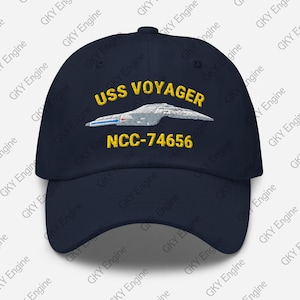 Può includere: Un cappellino da baseball blu navy con un ricamo che raffigura l'astronave USS Voyager in bianco e grigio. Sopra la nave, il testo USS VOYAGER è ricamato in giallo, e sotto la nave, il testo NCC-74656 è ricamato in giallo.
