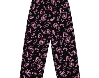 Puede incluir: Pantalón de pijama negro con un patrón de ataúd, corazón y colmillos rosa.