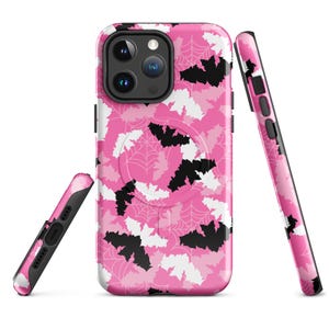 May include: A pink phone case with a Halloween design. The case displays a pattern of black and white bats, spiderwebs, and various shades of pink. The image shows the case from different angles, showcasing the design and the phone's camera.