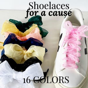 May include: A close-up of a pair of white sneakers with pink ribbon shoelaces. The text "Shoelaces for a cause" and "16 COLORS" is visible in the image.  The image also shows a variety of colorful ribbon shoelaces tied in bows.