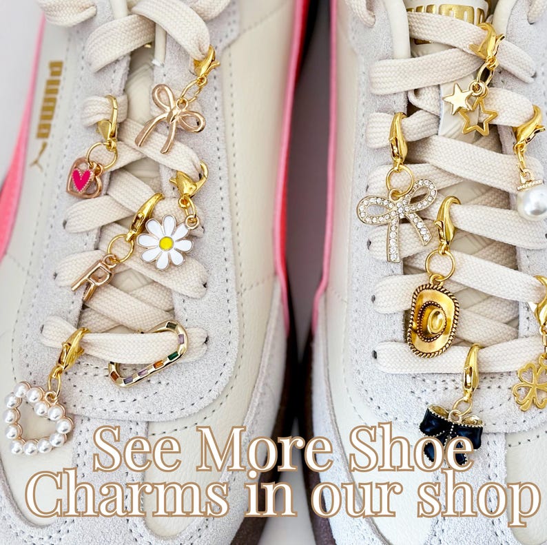 May include: Close-up of two white sneakers with colorful shoe charms attached to the laces. The charms include a heart, a daisy, a bow, a star, a cowboy hat, and a four-leaf clover. The text "See More Shoe Charms in our shop" is printed on the bottom of the image.